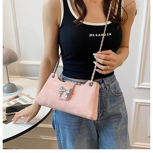 Détail d'un sac baguette rose avec nœud métallique argenté et bandoulière