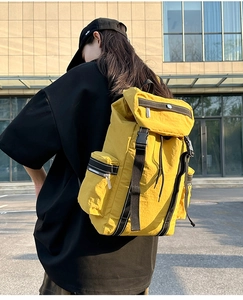 Detail of waterproof yellow roll-top backpack with durable black buckles and side zipper