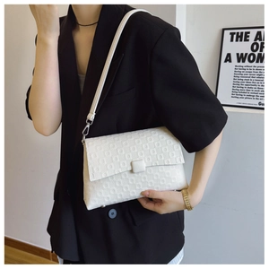 Detail of white PU shoulder bag featuring geometric embossed texture and square buckle