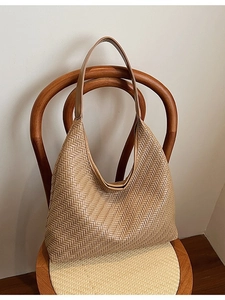 Retro woven camel shoulder tote bag in hobo style, displayed on a wooden vintage chair