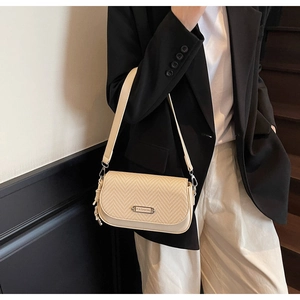 Détail du sac à bandoulière beige avec rabat tissé et boucle en métal rectangulaire