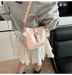 Detail view of beige crescent bag with smooth leather texture and elegant pearl bow charm
