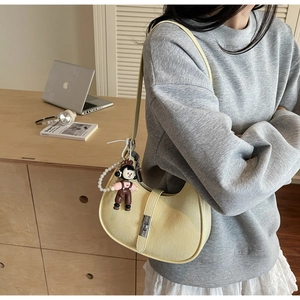 Detail of light yellow hobo bag with silver buckle and pearl charm on a model