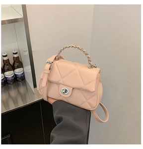 Close-up of peach pink quilted crossbody bag with metal chain handle and silver twist lock