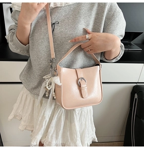 Detail of pink faux leather bucket bag with silver buckle and white lace pendant