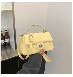Detail view of light yellow quilted crossbody bag featuring silver turn-lock and chain handle