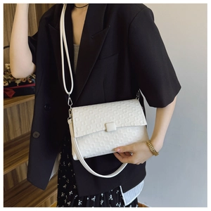 Detail of white textured shoulder bag with grid embossing and adjustable strap
