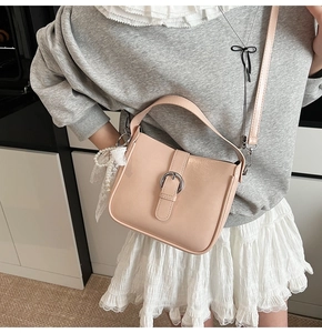 Close-up of pink leather shoulder bag with decorative silver buckle and pearl lace charm