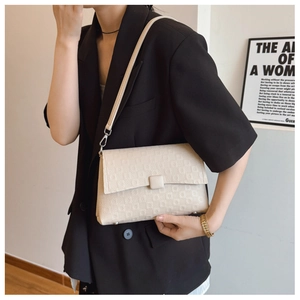 Detail of minimalist cream beige shoulder bag with geometric texture on a model