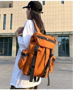 Close-up of orange water-resistant nylon backpack with buckles and top zipper pocket