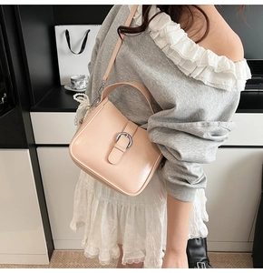 Detail of pink faux leather bag with silver buckle and pearl lace charm on strap