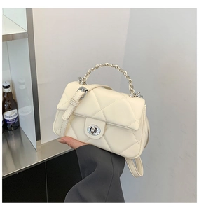 Detailed shot of beige quilted handbag featuring silver turn-lock closure and metal chain