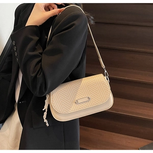 Détail de texture tissée et plaque en argent sur le sac à bandoulière blanc cassé