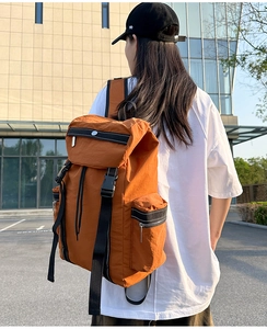 Detail of a burnt orange travel backpack featuring secure buckle closures and side zipper pockets