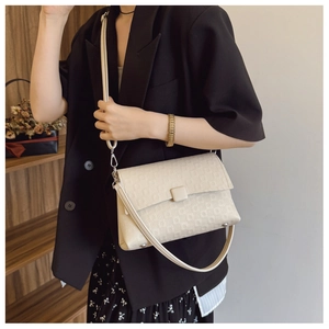 Detail view of cream-white textured flap bag with dual straps and geometric patterns