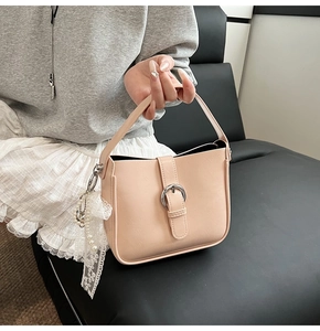 Detail view of beige leather tote bag with pearl lace charm and silver buckle