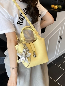 Bolso bucket de cuero amarillo claro con patrón de lichi y dije de estrella plateada
