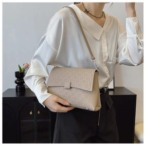 Detail of beige geometric pattern handbag with silver hardware on a crossbody strap