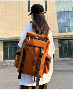 Close-up of orange nylon travel backpack with adjustable straps and side pockets