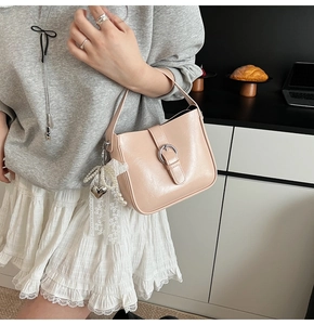 Detail of light pink faux leather handbag with pearl charm and silver buckle decoration