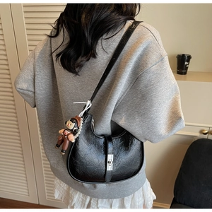 Close-up of black crescent bag featuring shiny wrinkled texture and silver swivel lock