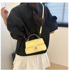 Rear view of yellow quilted crossbody bag with silver chain handle on female model