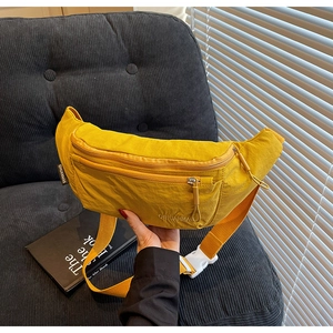 Detail of ginger yellow nylon sling bag showing fabric texture and adjustable strap buckle