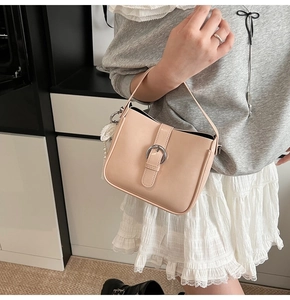 Detail of beige minimalist handbag with silver round buckle and pearl lace pendant
