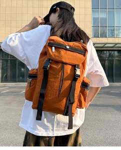 Outdoor shot of stylish orange-brown travel backpack with black straps and side pockets