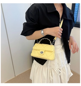 Close-up of pale yellow quilted crossbody bag with silver lock and metal chain handle