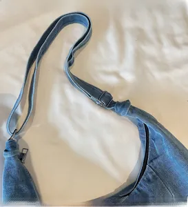 Detail of adjustable denim shoulder strap and smooth metal buckle on a blue tote bag