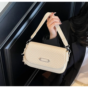 Détail du sac beige en paille et cuir avec plaque argentée FASHION et pompon décoratif