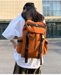 Detail of large orange nylon travel backpack with secure buckles and multi-pocket design