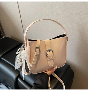 Detail of apricot bucket bag with pearl pendant and lace bow on textured leather