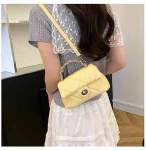 Detail of yellow quilted leather crossbody bag with silver chain and metal twist lock