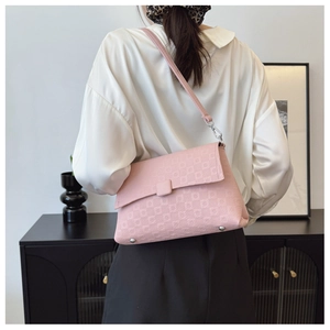 Detailed view of pink checkerboard embossed handbag worn as a stylish shoulder bag