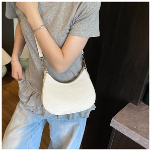 Detailed close-up of white crescent crossbody bag with lychee grain texture and gold clasp