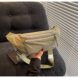 Detail of pea green fanny pack featuring double zippers and white buckle strap