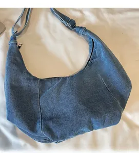 Detail of light blue washed denim moon bag with adjustable strap and silver hardware