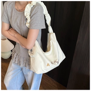 Détail d'un sac cabas blanc crème avec bandoulière plissée et broderie de la marque