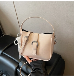 Detail view of cream beige PU leather tote with silver buckle and pearl lace charm accessory