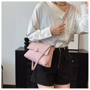 Detailed view of pink crossbody bag featuring geometric embossed texture and silver hardware
