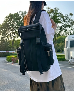 Side view of a black waterproof nylon travel backpack shown in an outdoor camping setting