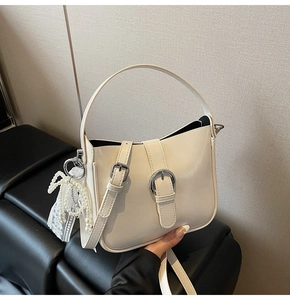 Detailed close-up of cream leather bucket bag showing lychee grain texture and silver buckle