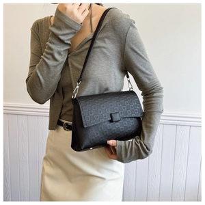 Detail of black embossed leather underarm bag with geometric patterns and silver buckle