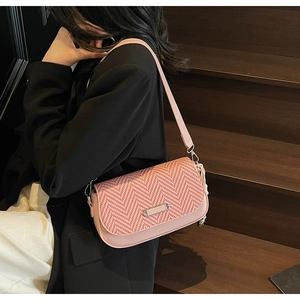 Détail du sac à main tissé rose avec logo métallique porté par un mannequin