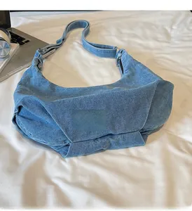 Detail of light blue denim crescent hobo bag with adjustable strap on white fabric