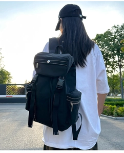 Outdoor view of a black hiking backpack with white contrast stitching and buckle closure