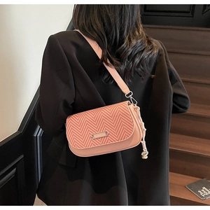 Détail d'un sac à main en cuir rose avec rabat à chevrons et breloque en nœud tissé