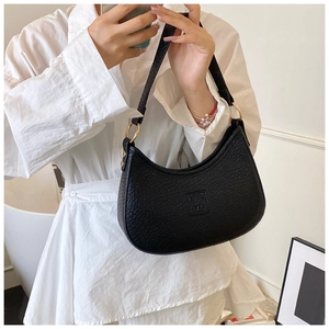 Close-up of black crocodile texture crescent shoulder bag with gold metal rings and logo
